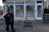 A man walks past a shop damaged by explosion in Mykolaiv