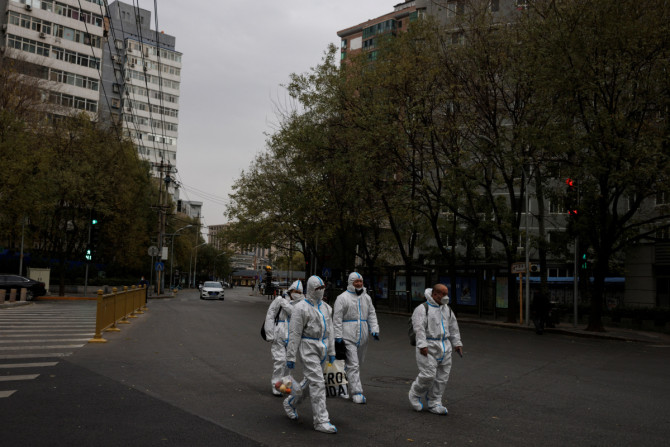 Men in protective suits walk in the street as COVID-19 outbreaks continue in Beijing