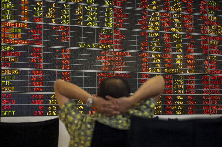 Thai investor sits in front of electronic board displaying live market data at stock broker's office in central Bangkok