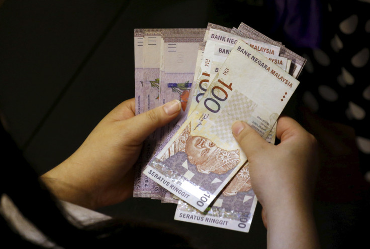 A customer counts her ringgit notes outside a money changer at the central business district in Singapore