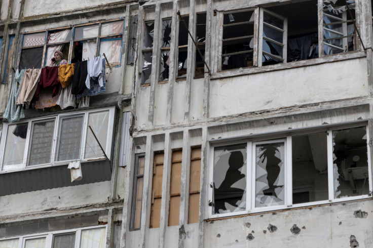 Local woman speaks on her mobile phone in a window of a residential building damaged by a Russian military strike in Kherson