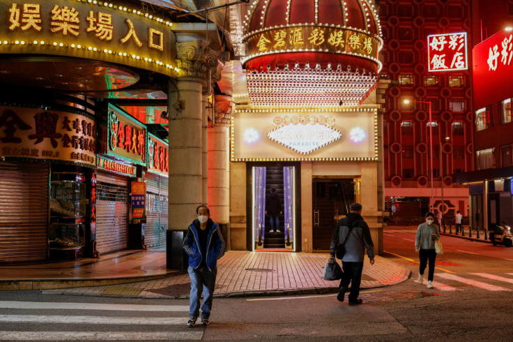 People wearing face masks walk under neon lights near casinos during the coronavirus disease (COVID-19) pandemic in Macau