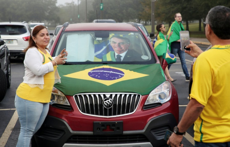 Brazilians take photos in front of a car adorned with a portrait of then President Jair Bolsonaro and a national flag after voting in Orlando, Florida, on October 30, 2022