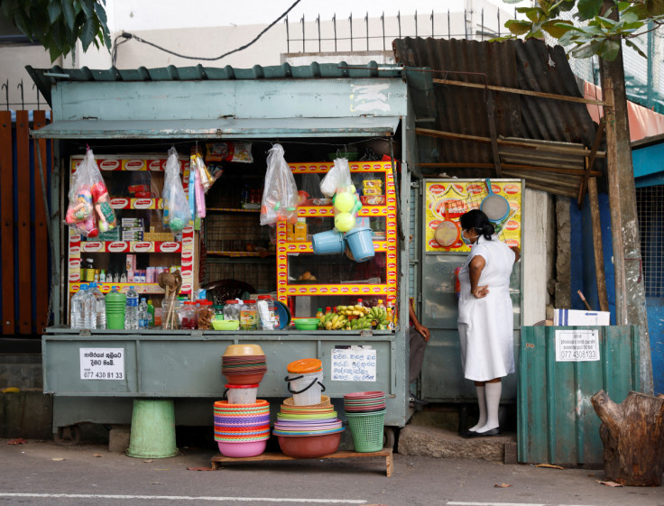 A medical worker talks to a vendor selling household goods and food for patients and their family members, outside Apeksha Hospital, Colombo