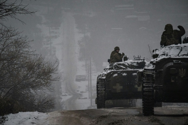 Ukrainian servicemen ride infantry combat vehicles driving down an icy road in the Donetsk region