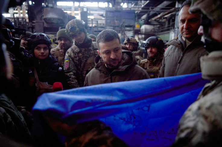 Ukrainian President Volodymyr Zelensky is gifted a Ukrainian flag bearing soldiers' signatures during a visit to the frontline town of Bakhmut