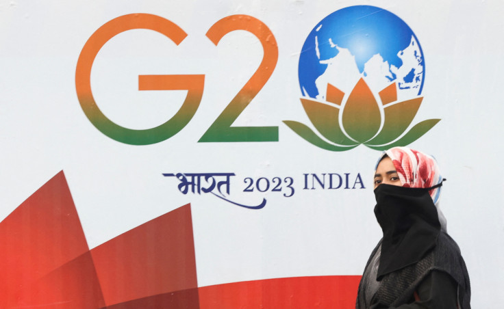 A woman walks past a hoarding of India's G20 presidency in Mumbai