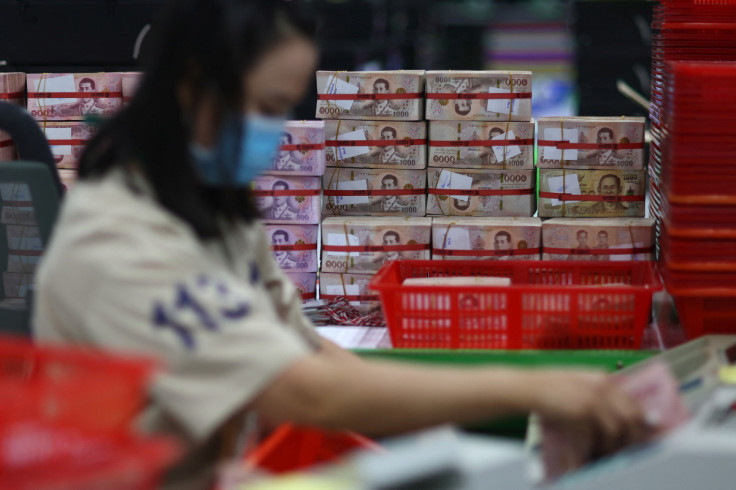 A bank employee gathers Thai baht notes at a Kasikornbank in Bangkok