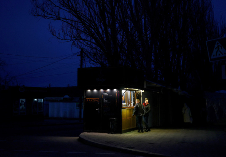 People stand by a coffee stall at dusk during power shortage in Mykolaiv