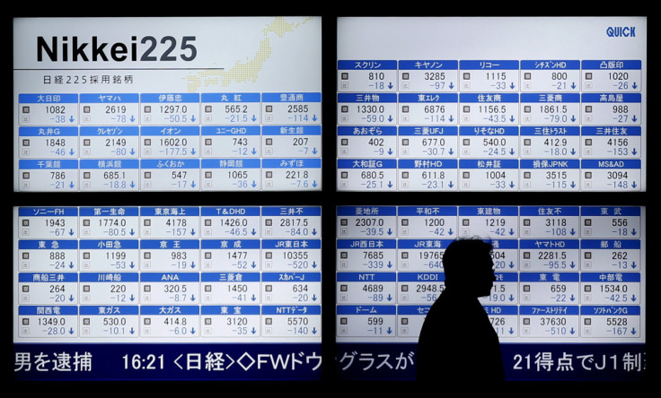 Man walks past an electronic board showing Japan's Nikkei 225 outside a brokerage in Tokyo