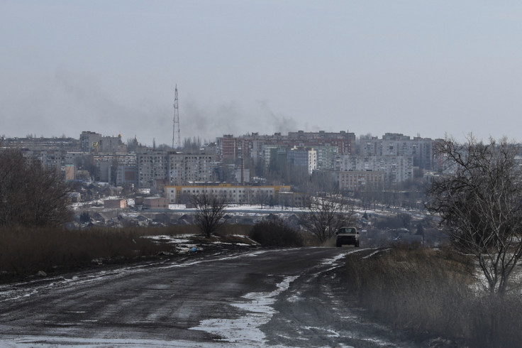 Smoke rises after a shelling as a car moves along a road in the frontline city of Bakhmut