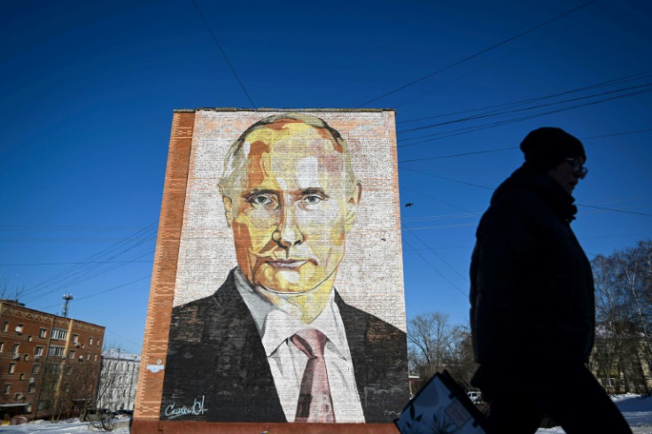 A woman walks past a mural of Russian President Vladimir Putin on a residential building in the town of Kashira, south of Moscow