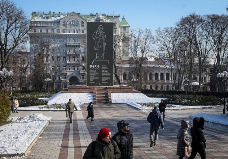 People walk in a park near the monument of Ukrainian poet Taras Shevchenko covered with a protective construction to protect against shelling in central Kyiv