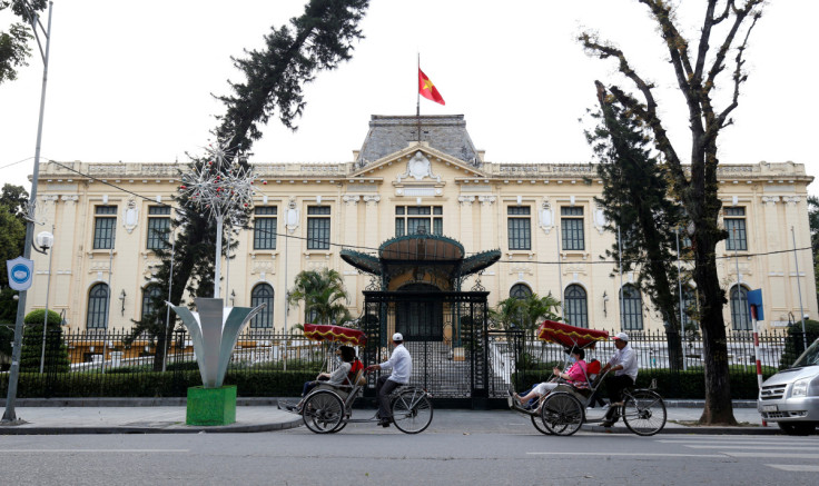 Men transport people on three-wheel cyclo past the Government Guesthouse in Hanoi