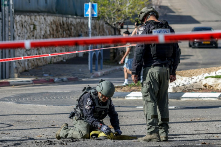 An Israeli police bomb disposal unit member inspects the remains of a shell fired from Lebanon and intercepted by Israel in its northern town of Fassuta