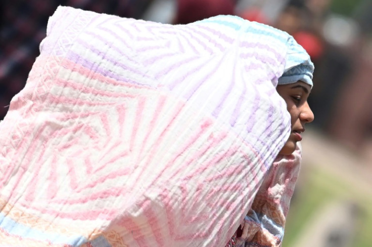 A woman covers herself with a scarf to shelter from the heat in New Delhi on Wednesday