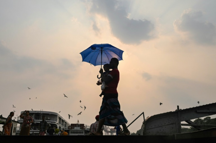 A man carrying his son walks with an umbrella during the heatwave in Yangon