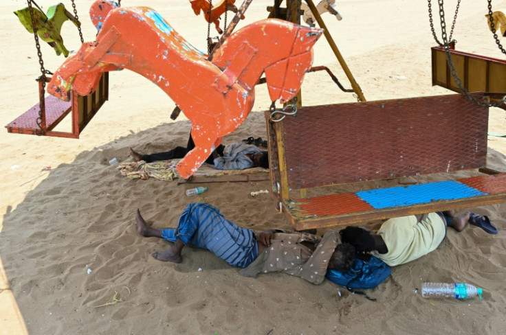 Workers rest under the shade of a merry-go-round ride in Chennai, India