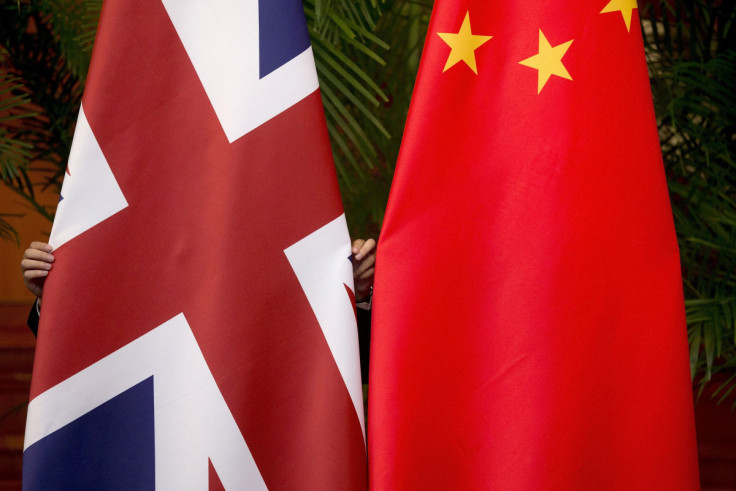 A worker adjusts British and China national flags on display for a signing ceremony at the seventh UK-China Economic and Financial Dialogue "Roundtable on Public-Private Partnerships" in Beijing