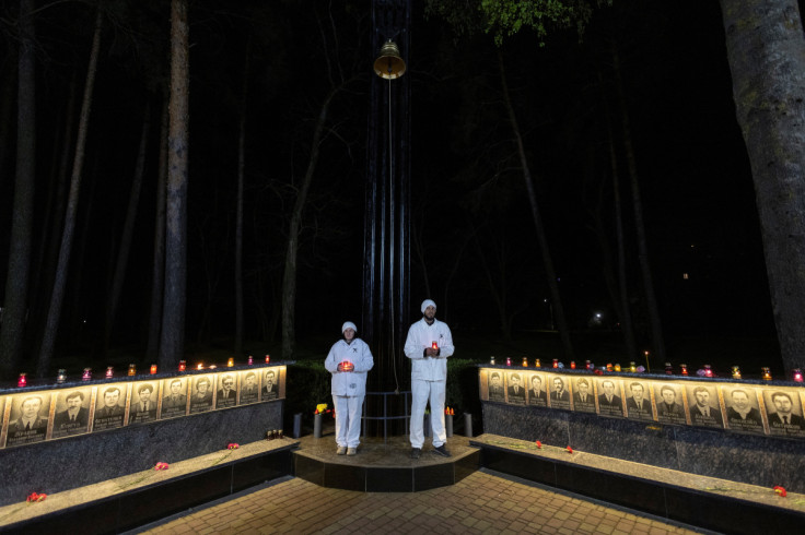 Staff of the Chornobyl nuclear plant hold candles at a memorial dedicated to firefighters and workers who died after the Chornobyl nuclear disaster, during a night commemorative service in Slavutych