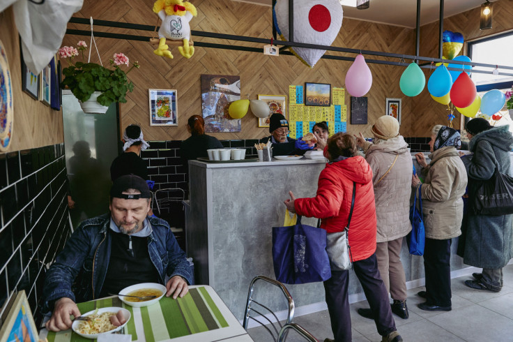 Humanitarian volunteer Fuminori Tsuchiko from Japan passes free food to people at his cafe in Kharkiv