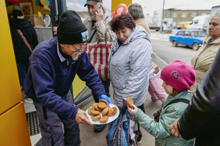 Humanitarian volunteer  Fuminori Tsuchiko from Japan treats a girl with cookies outside of his cafe in Kharkiv