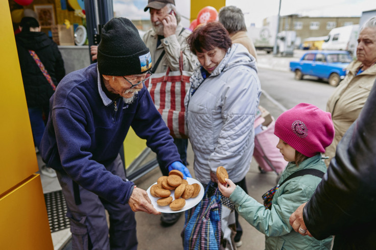 Humanitarian volunteer Fuminori Tsuchiko from Japan treats a girl with cookies outside of his cafe in Kharkiv
