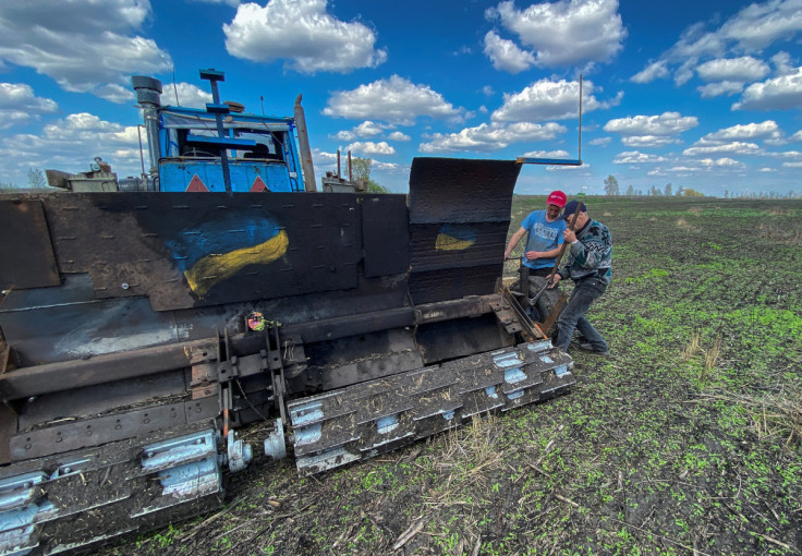 Workers fix a part of a remote controlled demining machine made of tractor and armoured plates from destroyed Russian military vehicles in a field near the village of Hrakove