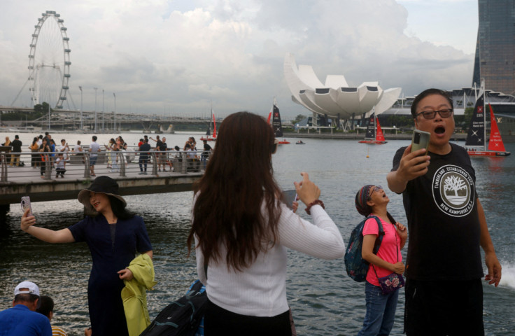 Chinese tourists pose for photos with the Merlion statue at Marina Bay in Singapore