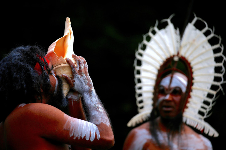 An Australian Aboriginal man blows into a shell as an indigenous man from the Torres Strait Islands wearing traditional dress performs during a welcoming ceremony at Government House in Sydney