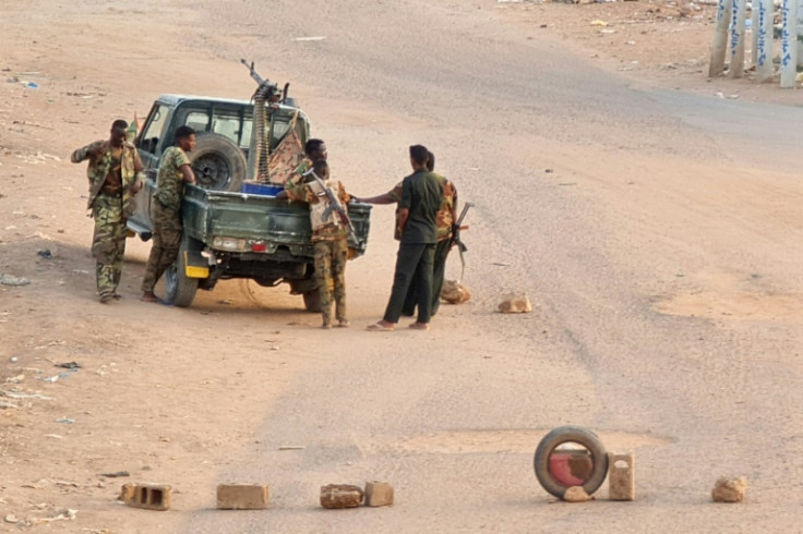 Sudanese army soldiers stand near their vehicle at a road block in Khartoum