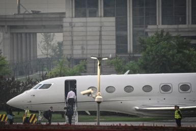Tesla chief Elon Musk (in white) boards his private jet before departing Beijing Capital International Airport on May 31