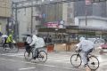 People riding bicycles make their way in the heavy rain in Kochi
